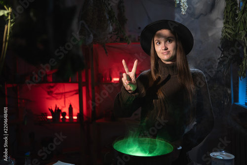 Картината върху платно Realistic witch brewing a potion in cauldron showing victory V gesture