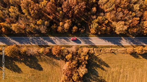 Top Down Drone View of Red Camper Van Driving on Straight Country Road in Autumn