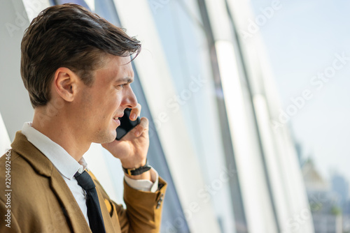 Businessman on mobile phone call by window in city office