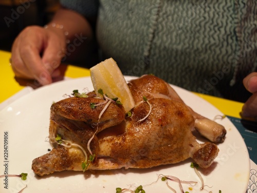 Fotografie Whole roasted chicken garnished with herbs and lemon on a white plate