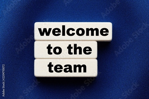 White wooden blocks spell welcome to team on blue textured background. Minimalist message sign for new employee onboarding. Corporate greeting concept for staff induction, recruitment, business