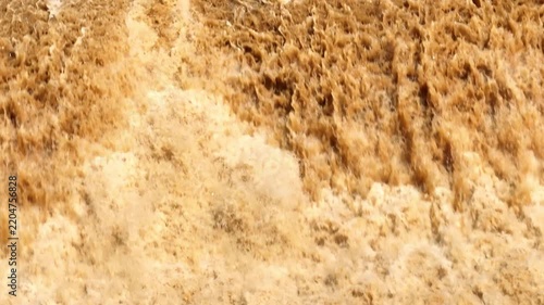 Drone perspective reveals fierce brown floodwater and foaming currents, conveying severe rainfall, climate extremes, natural hazards, water erosion and increasing flood risk. Phrae Province, Thailand.