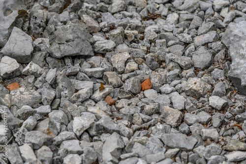 Grey limestone rubble and brick fragments texture with a small orange butterfly, natural stone background