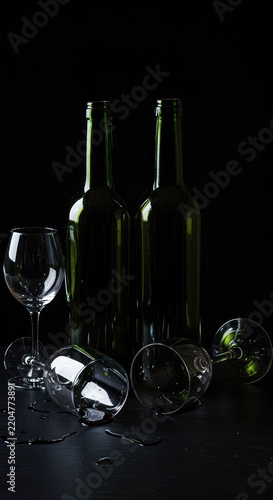 Empty wine bottles and stained glasses scattered on a dark table, representing excessive alcohol consumption and the effects of intoxication ,consumption ,red ,glass