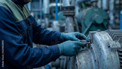 Vibration sensor installation and predictive maintenance concept, worker in gloves mounting iot sensor on electric motor in factory pump room for condition monitoring and equipment inspection