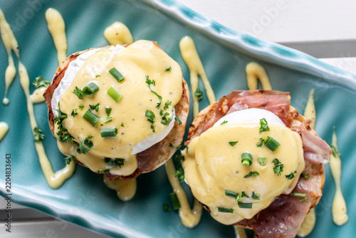 Eggs Benedict breakfast food on white table at modern restaurant cafe outdoors
