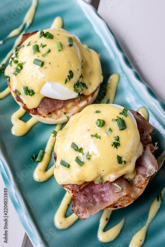 Eggs Benedict breakfast food on white table at modern restaurant cafe outdoors