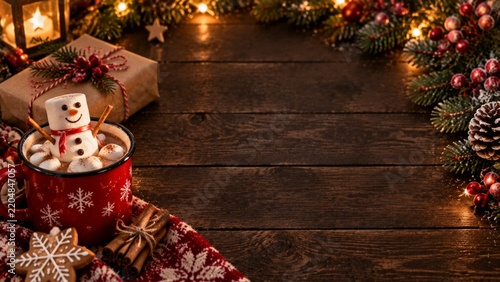 Decorative Red Mug With Marshmallows and a Snowman on a Wooden Table During t...