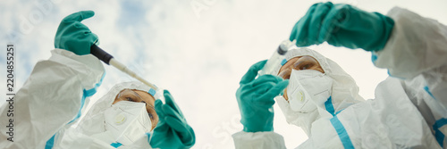 Foto Header of scientists in hazmat suits collecting outdoor samples with pipette and test tube
