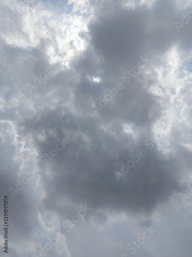 Sunlight filtering through dramatic dark gray clouds in a blue sky.