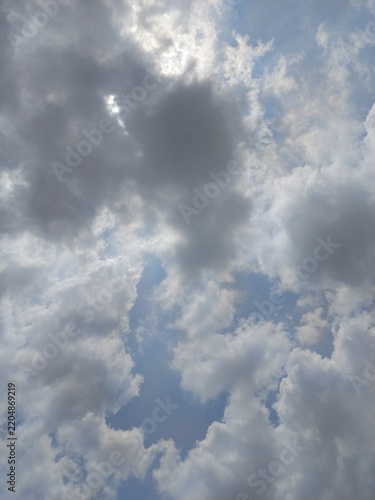 Sunlight filtering through dramatic dark gray clouds in a blue sky.