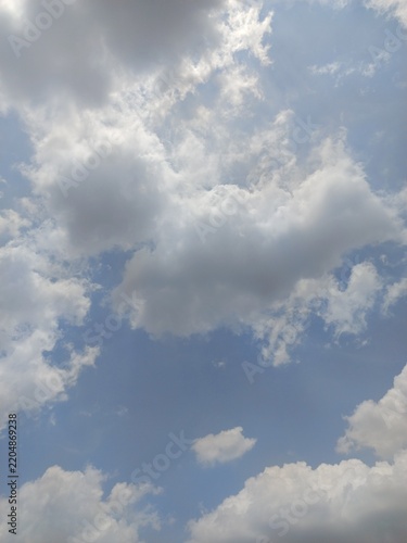 Fluffy white clouds scattered around a clear blue sky on a bright sunny day.