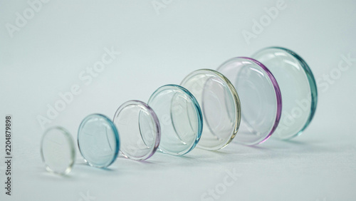 Progressive arrangement of circular glass lenses on neutral background as isolated element