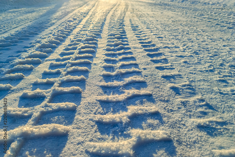 Obraz premium Tire tracks on winter snow road background for life journey concept and future dreams inspiration. Clear car tire track marks heading towards the bright horizon on a snowy path