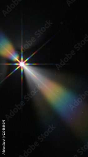 Brilliant starlight burst featuring prismatic rainbow lens flare on black background as isolated element