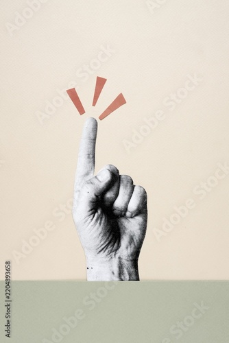 Cutout hand pointing index finger up with exclamation marks on beige background