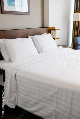 Modern hotel bedroom interior with comfortable bed and blue armchair