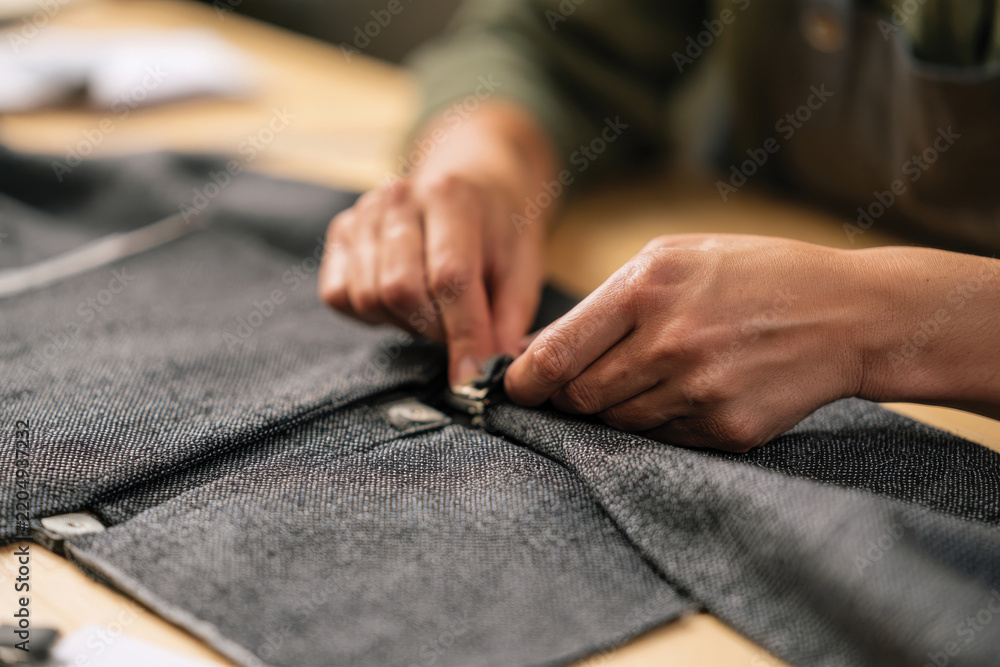 Fototapeta premium Hands expertly secure fabric fasteners, demonstrating the intricate work involved in garment creation, capturing the essence of craftsmanship and attention to detail.