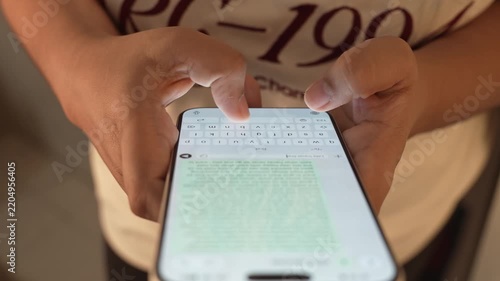 Woman's hand chatting and typing on a smartphone, macro closeup. Unrecognisable human typing a text message, tapping the touchscreen keyboard using the WhatsApp application, a social media.