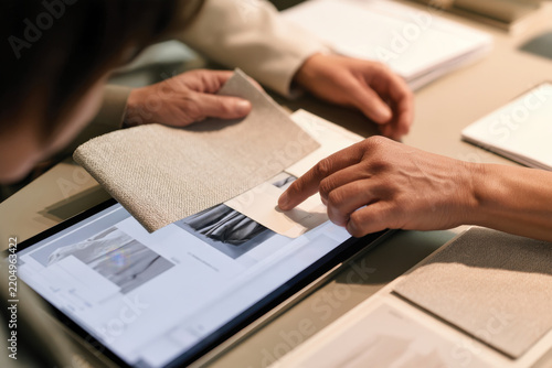 Two individuals engage digitally, exploring fabric samples on a tablet, emphasizing modern technology's role in selecting materials for fashion design.