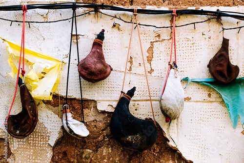 Traditional Spanish leather wineskins hanging on a rustic adobe wall.
