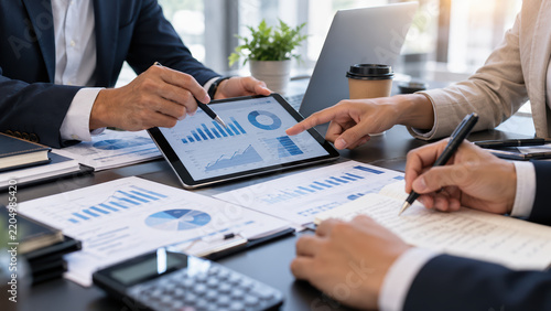 Business team analyzing financial reports using tablet and charts to discuss marketing data corporate strategy investment growth performance review professional collaboration accounting analysis