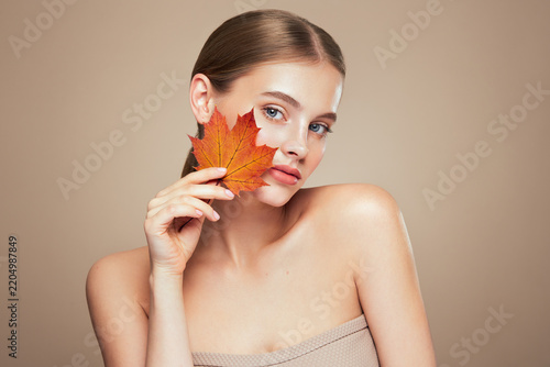 Portrait of beautiful young woman with autumn leaves. Healthy clean fresh skin natural make up beauty eyes