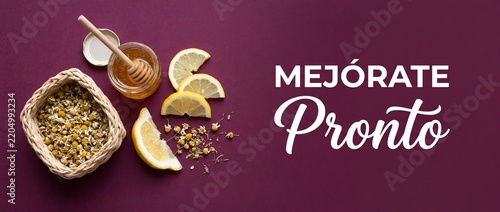 Mejorate pronto get well soon Spanish greeting card with honey lemon and dried chamomile flowers flat lay for natural cold remedy wellness health treatment and speedy recovery concept background