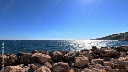Sparkling blue sea of Cassis on a sunny day, French Riviera, Provence-Alpes-Côte d'Azur, France, Europe. Sun reflecting on the sea behind a rocky breakwater in Cassis, Bouches-du-Rhône, France, Europe