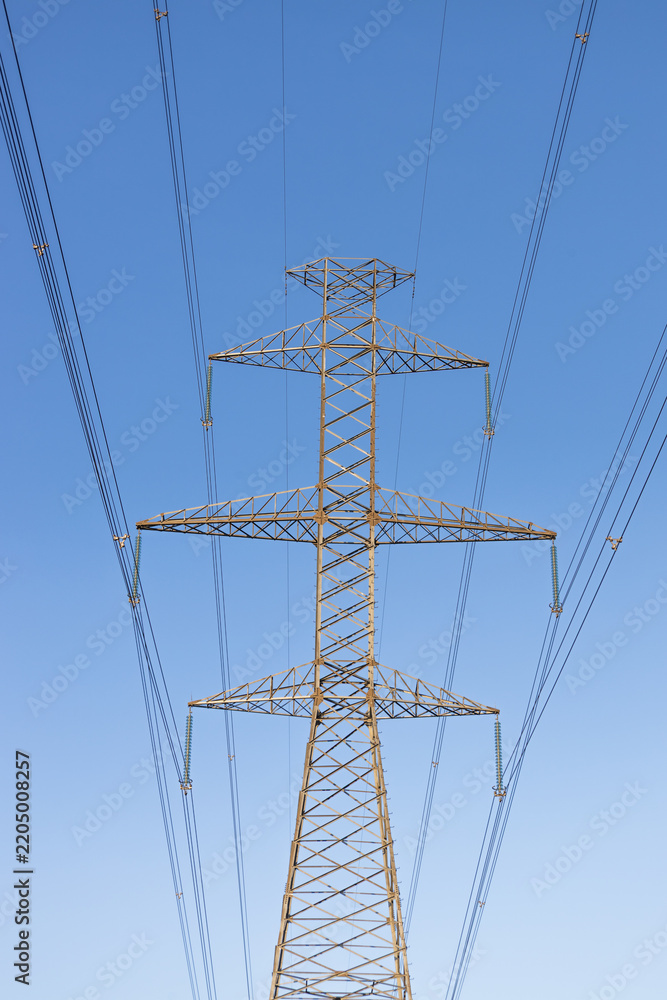 Obraz premium Electric power transmission pylon against a clear blue sky
