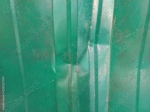 Green corrugated iron roofing sheet with crumpled dent texture.