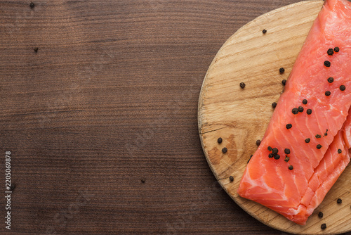 Seasoned salmon on cutting board on brown wooden table with copy space.