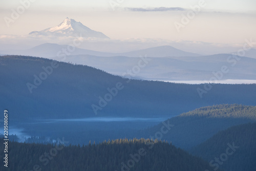 Distant Mount Jefferson rising above layered forested ridges, viewed from Mount Hood in Oregon