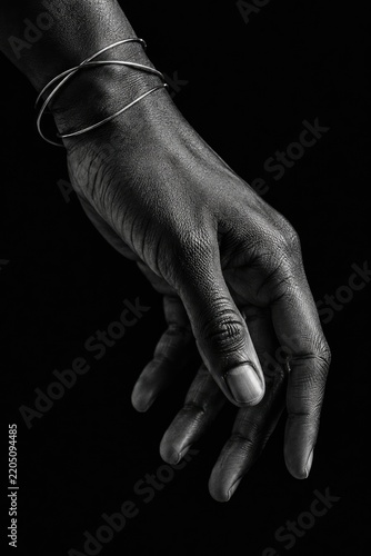 Close-up portrait of elegant human hand adorned with minimalist silver wire bracelet against stark black background for modern branding and editorial use