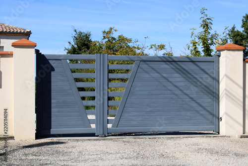 Portail battant moderne automatique en aluminium gris anthracite au design asymétrique ajouré