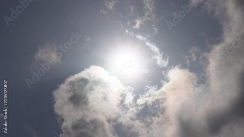 Bright sunlight shining through textured clouds in blue and grey sky