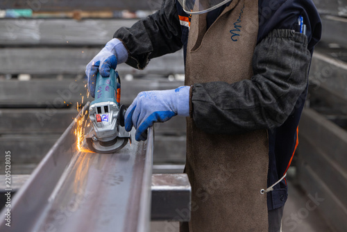 Industrial Worker Grinding Steel Beam with Sparks in Factory