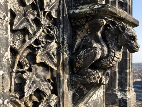 Carved stone panel of vine leaves beside a squat dragon corbel