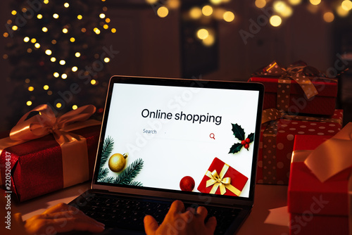 Sign Online shopping on laptop screen against glowing Christmas lights in a dark domestic setting room
