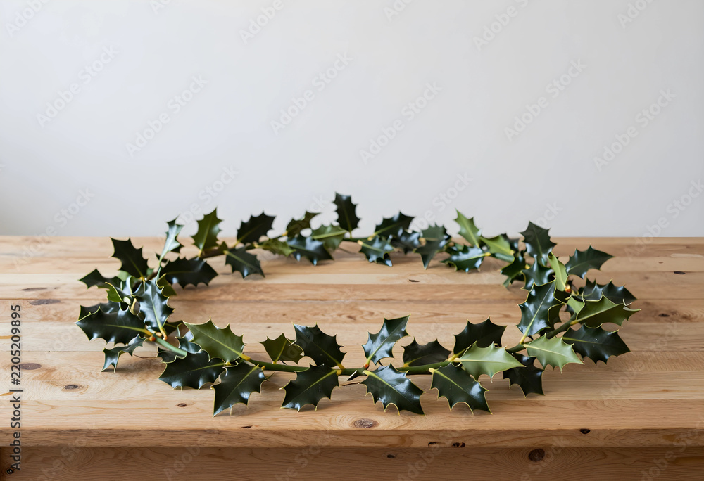 Obraz premium Christmas holiday decoration, holly wreath on rustic wooden table for festive winter season celebration and home interior design with copy space