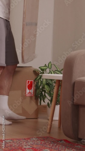 Young man unpacking cardboard boxes in new apartment room