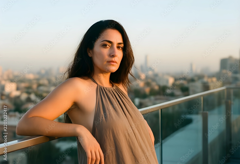 Fototapeta premium Urban lifestyle and mental wellness, thoughtful woman looking at city skyline from balcony at sunset for reflection and personal growth in modern city