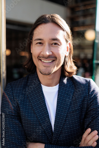 Smiling man in blazer with arms crossed.