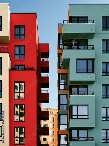 Colorful modern colorful buildings built side by side create striking visual contrast against clear blue sky. vibrant red and green facades architectural design, unique aluminium window