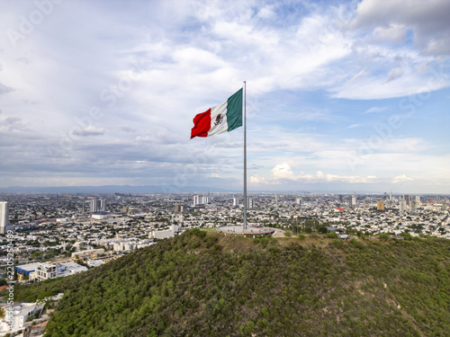 Aerial view of the Mexican flag waving atop the Cerro del Obispado overlooking the urban landscape of Monterrey, Nuevo Leon, Mexico.