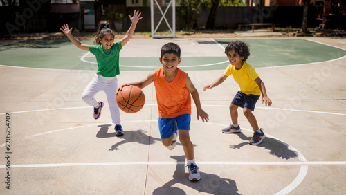 Group of Happy Indian Children Playing Basketball on Outdoor Court During Sunny Day Sports