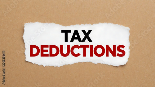 Tattered paper note with tax deductions text on brown cardboard background