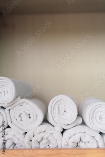 Clean white fresh towels neatly stacked on top of each other in shelf near swimming pool