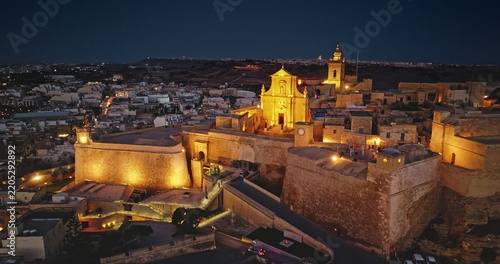 Aerial view of the illuminated Cittadella fortifications and cathedral at night in Victoria, Gozo, Malta.