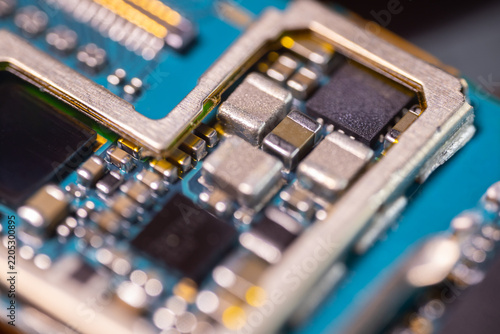 Macro view of miniature electronic components, metallic contacts, dark chips, and blue circuit board traces in a detailed technology hardware close up